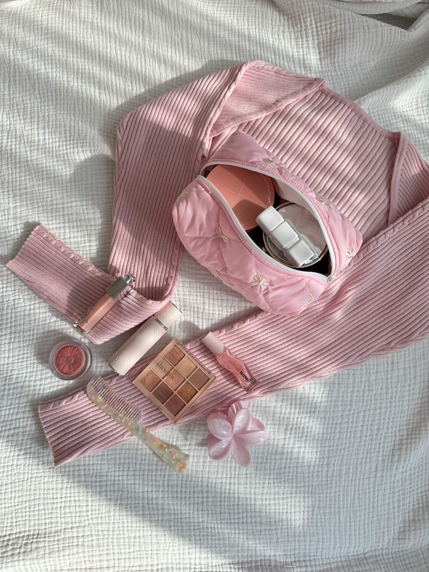 Clean girl routine with pink Ribbon Puff pouch & beauty items on a soft bed