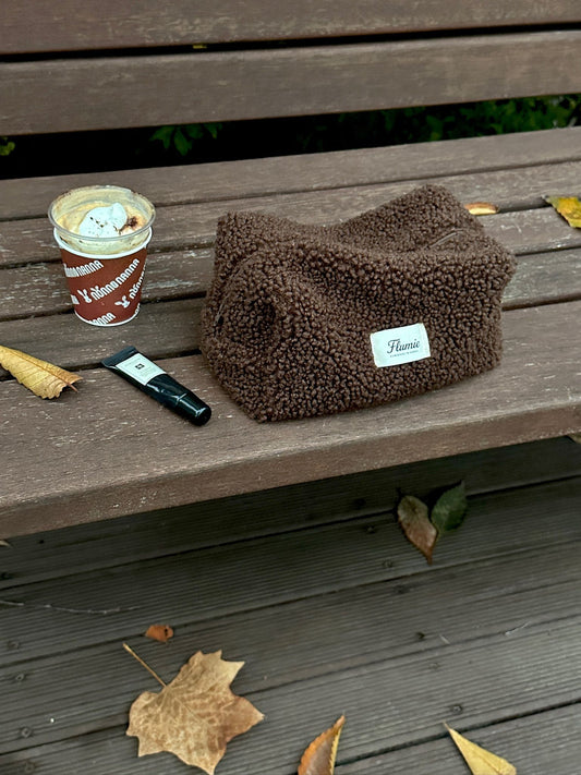 Flumie’s cocoa pouch on a wooden bench with hot drink, expressing a calm and cozy winter afternoon