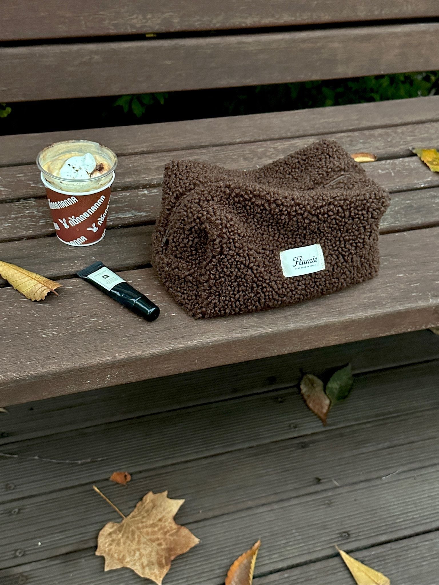 Flumie’s cocoa pouch on a wooden bench with hot drink, expressing a calm and cozy winter afternoon