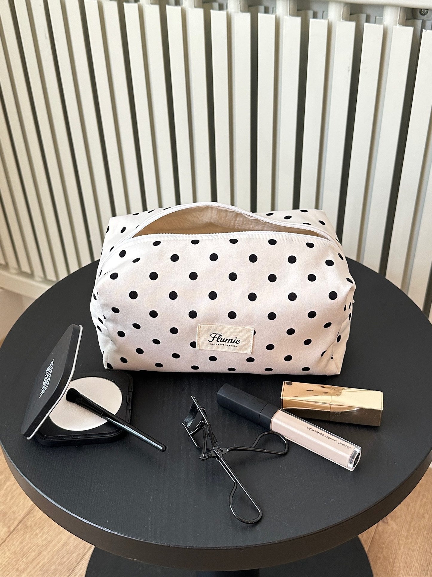 Ivory dot pouch styled with soft makeup items, offering a clean and girly mood