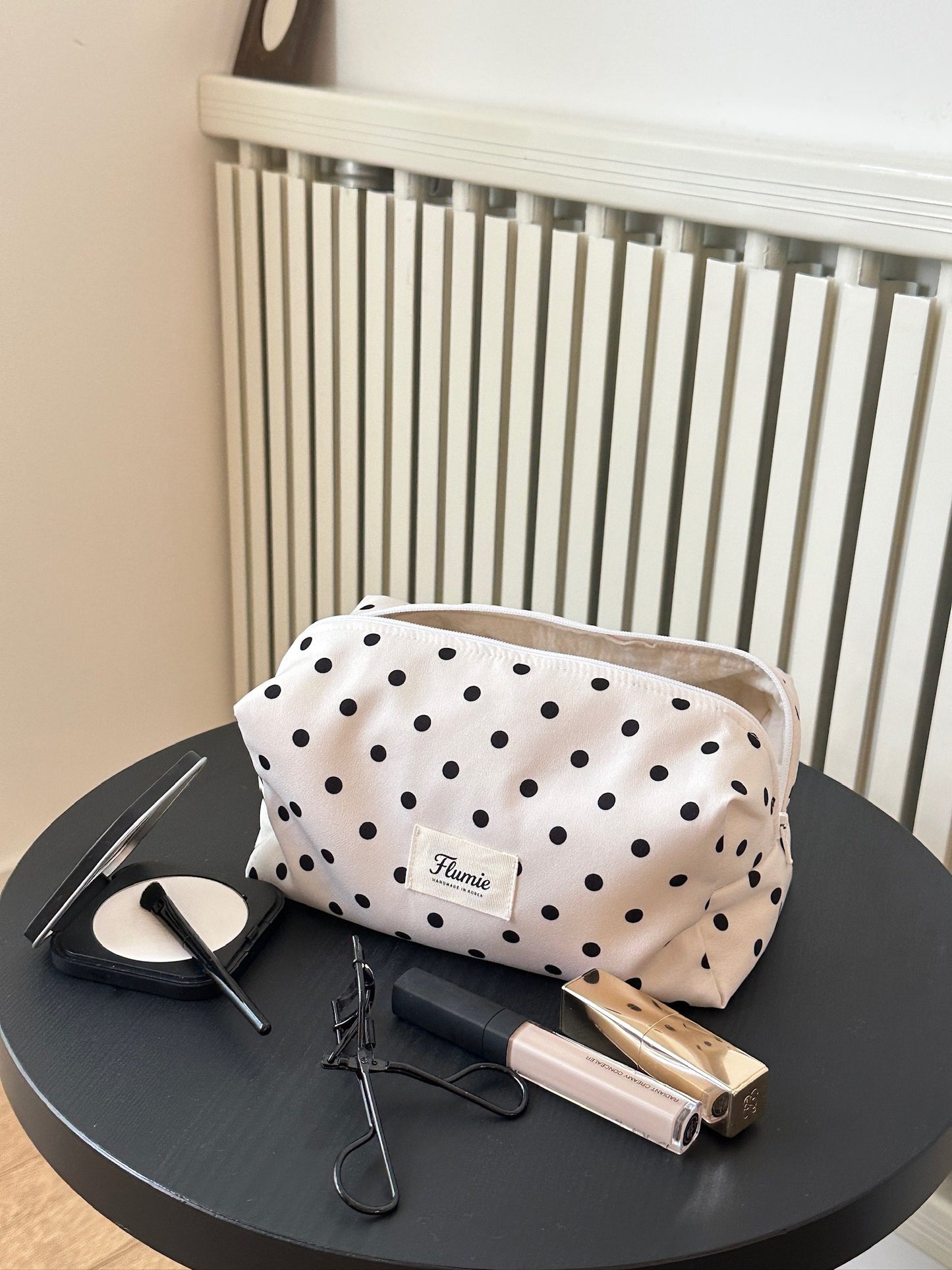 Ivory dot pouch styled with soft makeup items, offering a clean and girly mood