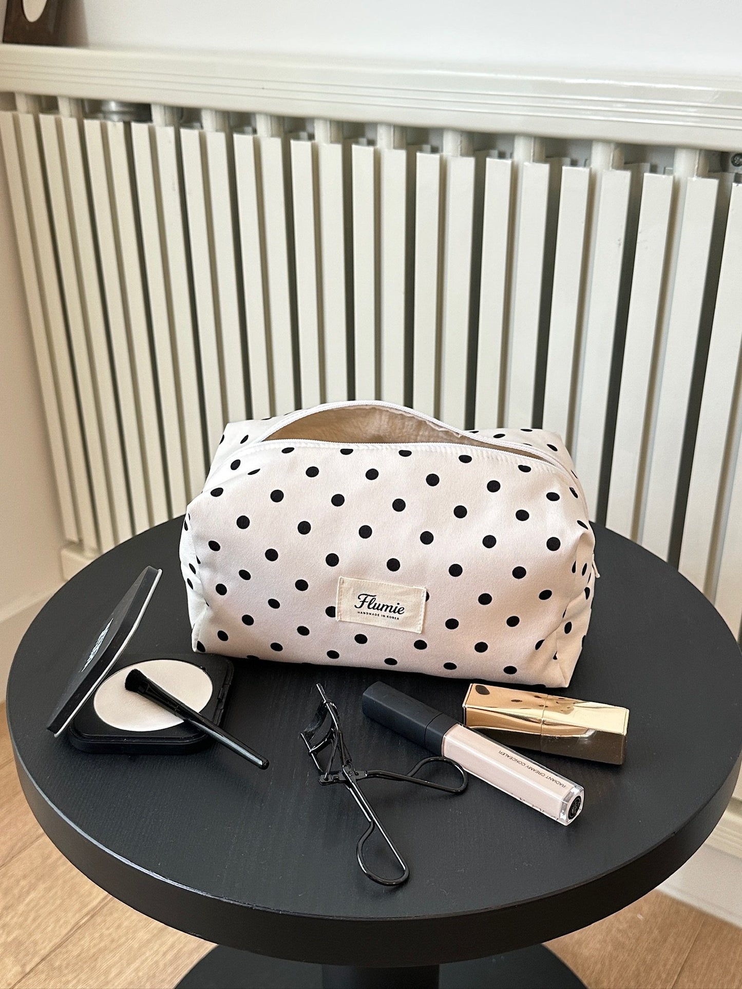 Ivory dot pouch styled with soft makeup items, offering a clean and girly mood