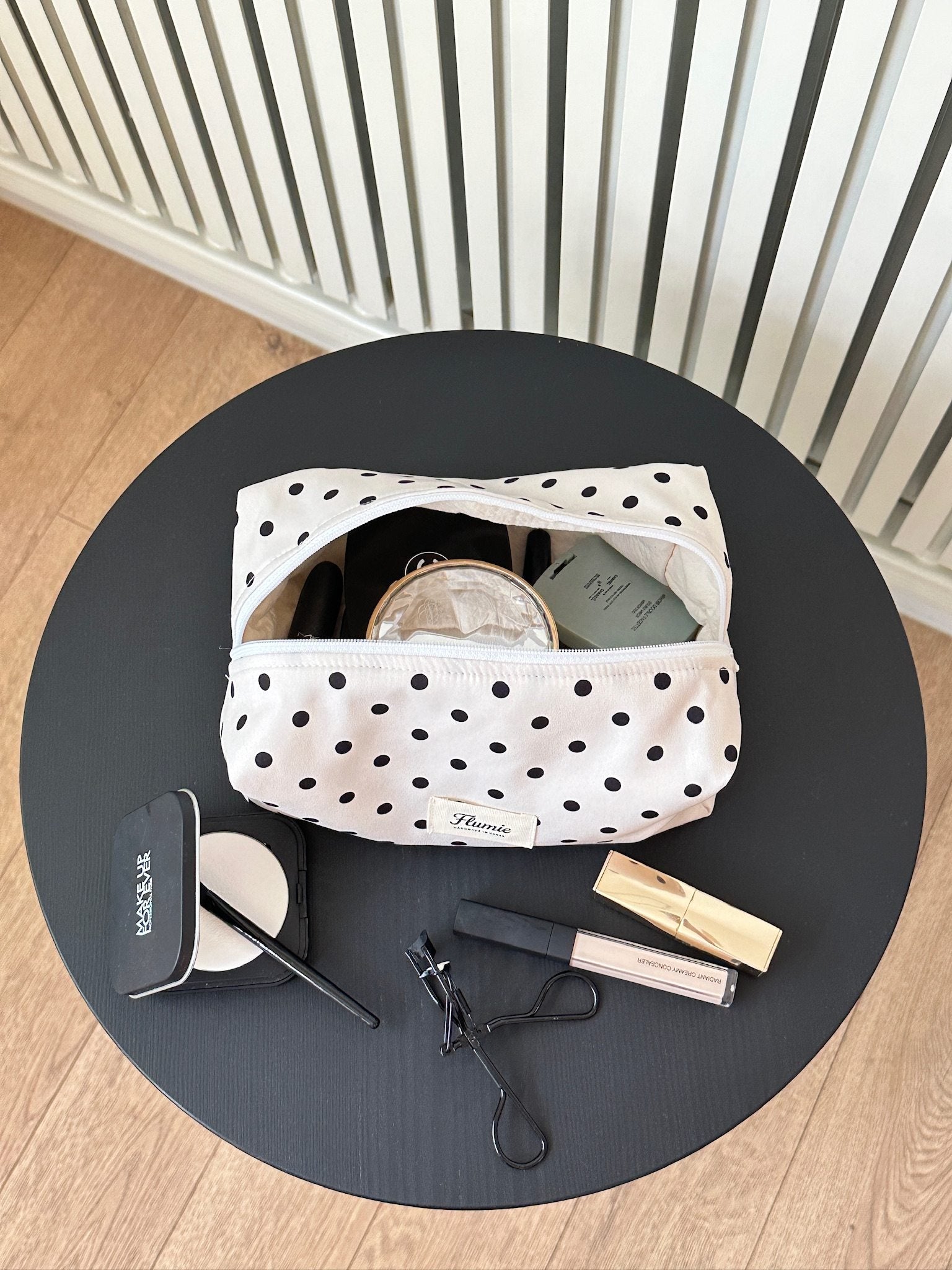 Ivory dot pouch styled with soft makeup items, offering a clean and girly mood