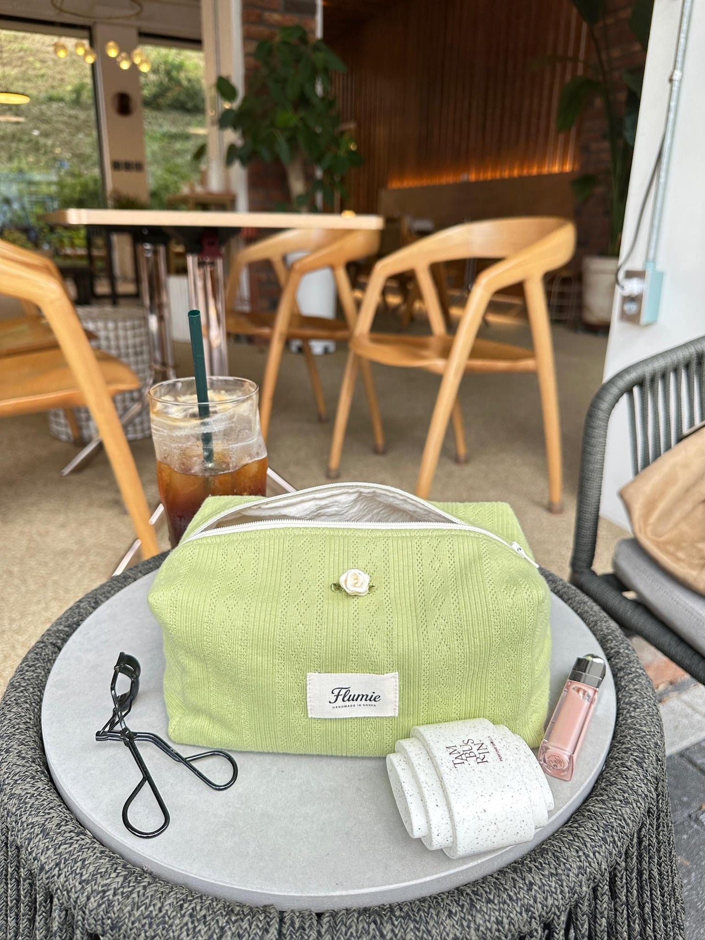 Soft green knit pouch styled in a cozy café scene, perfect for fall routines and aesthetic daily bags