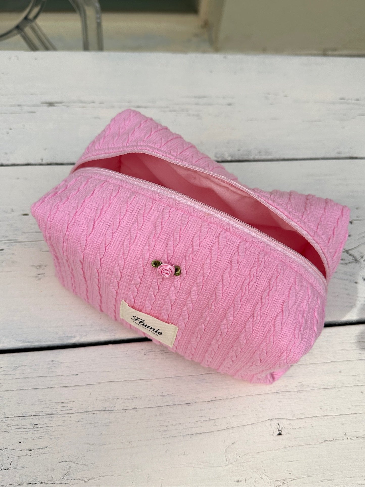 Strawberry pink cable knit pouch with rose detail, exuding a warm and sweet feeling
