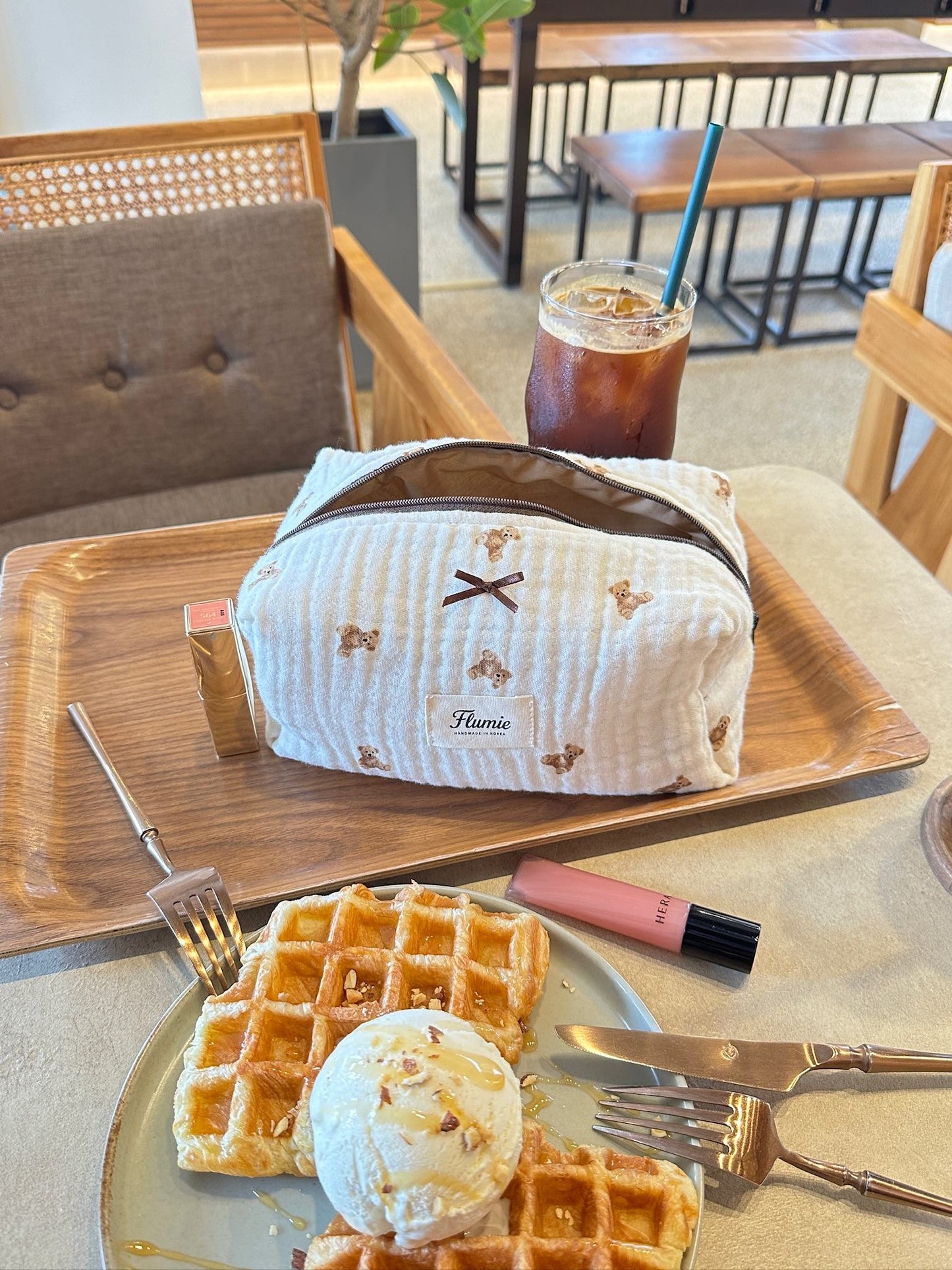 Teddy bear pouch placed next to sweet dessert and pink lip gloss, capturing a cute and gentle vibe